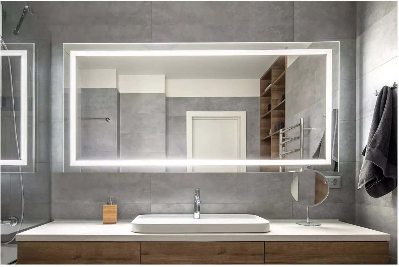 LED mirror for bathroom mounted on glass mosaic tiles above a recessed marble sink in Leicester.